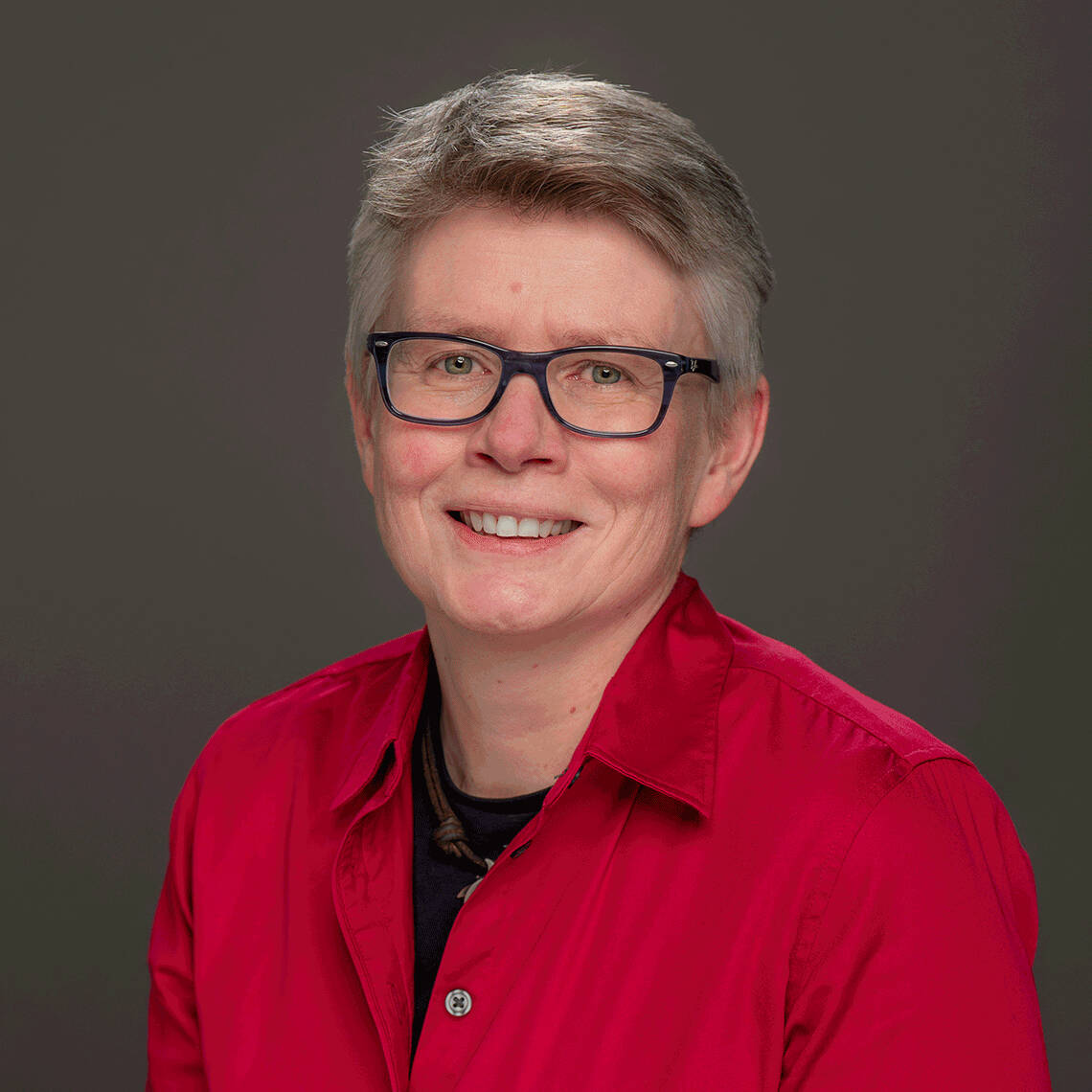 Dr. José wearing a red shirt and black-framed glasses